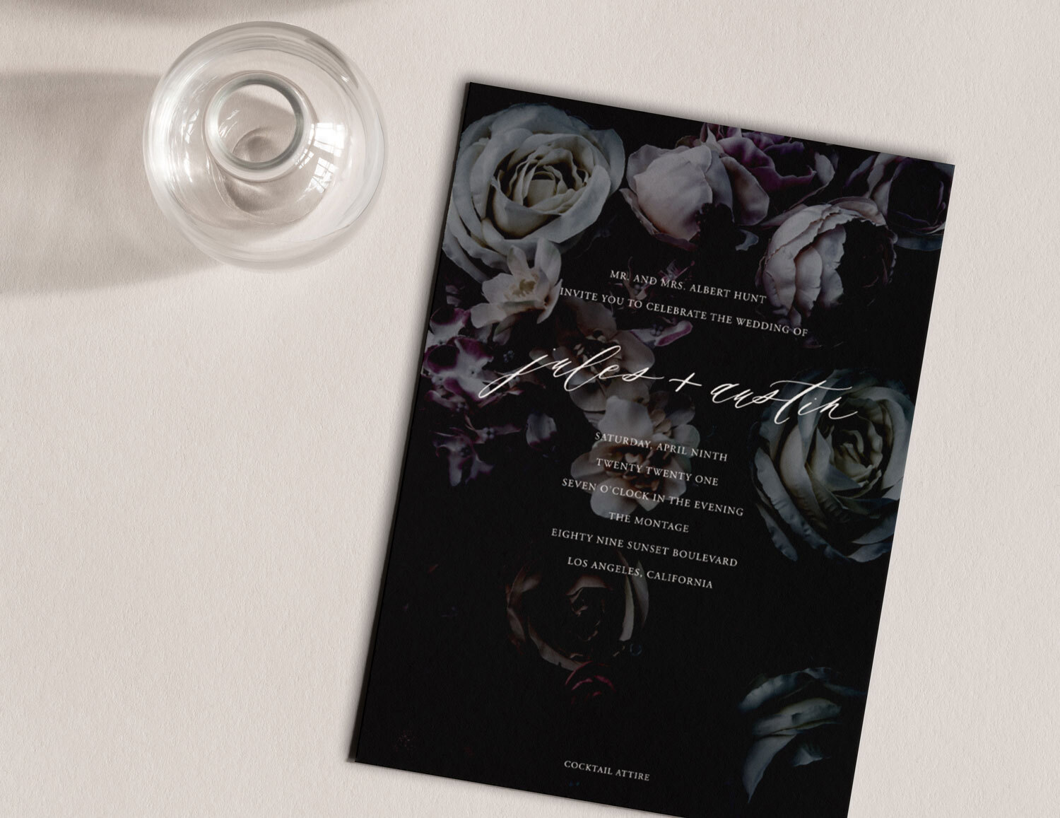 An overhead view of a black and white floral wedding invitation on a tabletop