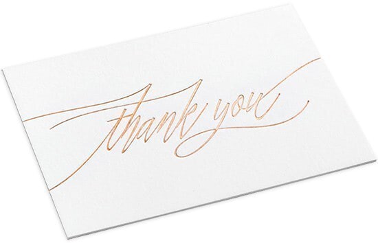 A white thank you note with gold script