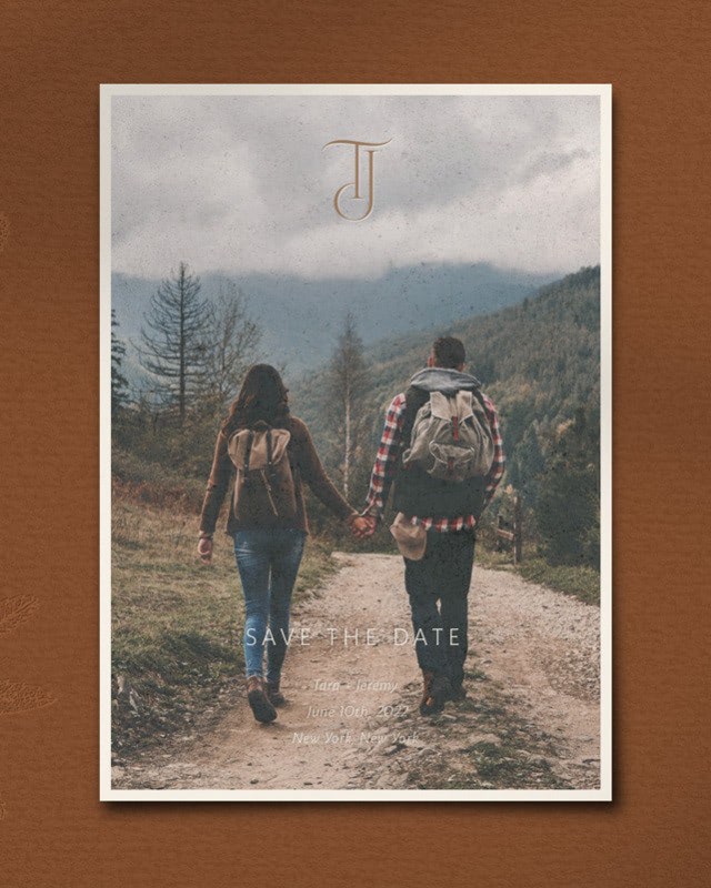 A photo Save the Date with a couple holding hands while walking along a hiking trail