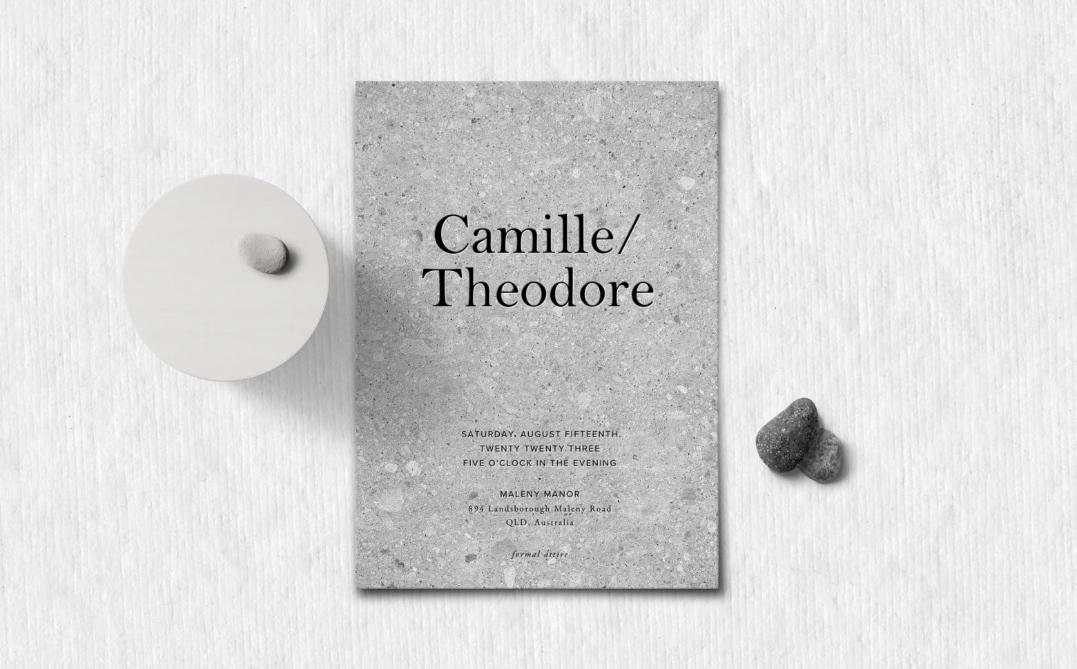 An overhead view of a gray wedding invitation for a couple named Camille and Theodore
